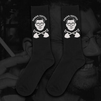 Black socks by Hate Couture Clothing featuring white embroidered portrait with glasses and crossed shovels design, labeled “CHAUX-SSETTES”, inspired by dark humor and true crime fashion.