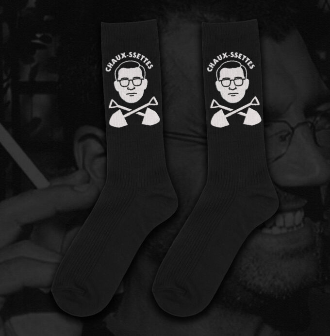 Chaux Ssettes Black socks by Hate Couture Clothing featuring white embroidered portrait with glasses and crossed shovels design, labeled โCHAUX-SSETTESโ, inspired by dark humor and true crime fashion.